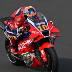 Luca Marini en su moto Honda número 10, con su traje rojo y azul, compite en la pista.