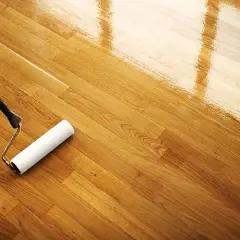 Rodillo aplicando barniz para limpiar parquet y darle un acabado brillante.