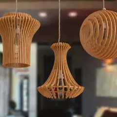 Tres lámparas de techo de madera con diseño moderno. Una pantalla lámpara techo infantil con forma de campana, otra similar pero más pequeña, y una esférica.