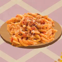 Un plat de malloreddus alla campidanese, pâtes traditionnelles sardes, servi sur une assiette dorée.