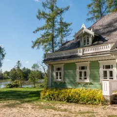 Zielony, drewniany dom z werandą i ozdobnymi detalami, nad jeziorem. Idealne miejsce na białowieża plan zwiedzania.