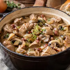 Un réconfortant sauté de veau mijoté avec des champignons, des oignons et des lardons, garni de thym frais. Parfait pour un repas d'automne.