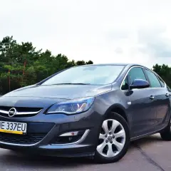 Szary Opel Astra 2025 na tle sosnowego lasu. Elegancki sedan gotowy na każdą podróż.
