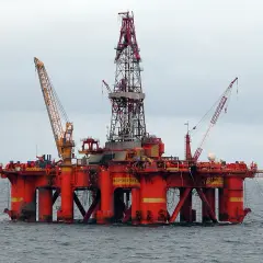 Ogromna, pomarańczowa platforma wiertnicza na morzu, symbolizująca wysokie zarobki na platformie wiertniczej w Norwegii.