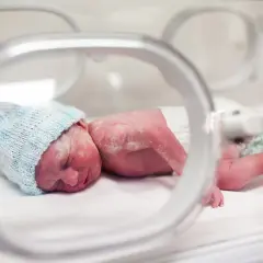 Noworodek w inkubatorze, zmagający się z wyzwaniami przedwczesnego porodu.