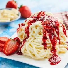 Ein köstliches Spaghetti-Eis-Dessert mit Erdbeersauce und frischen Erdbeeren, garniert mit weißer Schokolade.
