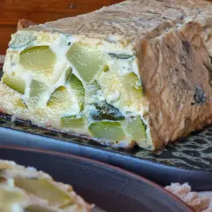 Pastel de calabacín casero, con trozos verdes visibles en una masa dorada, servido en plato oscuro.