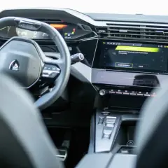 Nowoczesne wnętrze Peugeot 408 z cyfrowymi zegarami i ekranem dotykowym. Widoczny fragment kierownicy i konsoli środkowej.