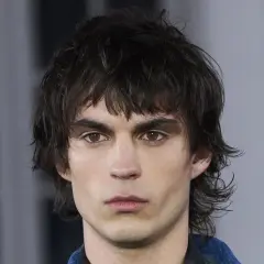 Hombre con un moderno mullet de pelo corto, mirada intensa y cejas marcadas.