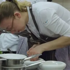 Chef prepara ingredientes en un mortero, escena digna de películas sobre cocina.