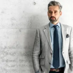 Elegancki mężczyzna w jasnej marynarce, która idealnie podkreśla sylwetkę. Wzorowa stylizacja, jak powinna leżeć marynarka.