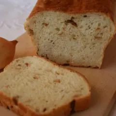 Pyszny chleb cebulowy na drożdżach, świeżo upieczony, z widocznymi kawałkami cebuli w miękiszu. Obok leżą całe cebule.