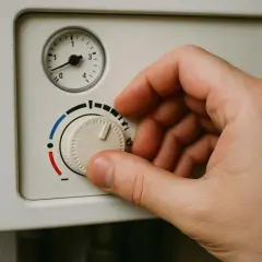 Dłoń kręci pokrętłem pieca gazowego, pokazując jak ustawić piec gazowy bez sterownika. Skala od czerwonego do niebieskiego oznacza temperaturę.
