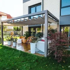 Nowoczesna pergola z wysuwanym dachem na tarasie z drewnianą podłogą i meblami ogrodowymi.