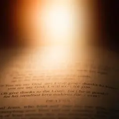 Otwarta Biblia, światło pada na tekst: "łaską jesteśmy zbawieni". Wersety Psalmów i modlitwa.