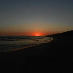 Wschód słońca Krynica Morska. Słońce wschodzi nad Bałtykiem, malując niebo pomarańczem. Fale delikatnie szumią na plaży.
