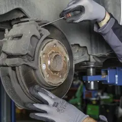 Mechanik w rękawiczkach sprawdza hamulce, by uniknąć bicia przy hamowaniu z dużej prędkości.