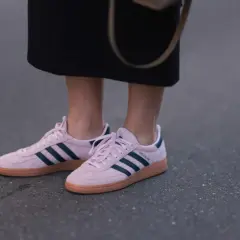 Różowe buty sportowe Adidas z granatowymi paskami i brązową podeszwą.