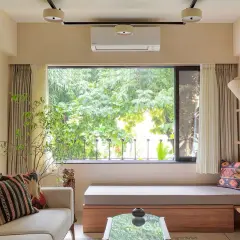 Cozy living room with a large window overlooking lush greenery, a comfortable sofa, and a built-in bench, making this small house feel spacious.
