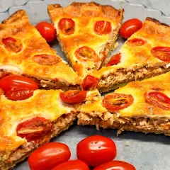 Kawałki pysznej tarta z kurczakiem i pomidorkami koktajlowymi, podane w szklanej formie.