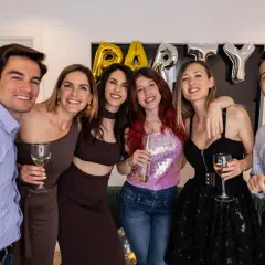 Impreza w stylu PRL! Jak się ubrać? Grupa przyjaciół świętuje, jeden mężczyzna w niebieskiej koszuli, kobiety w modnych kreacjach.