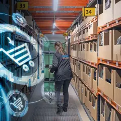 Kobieta w magazynie, gdzie nowe technologie w logistyce wizualizują procesy. Wózki i koszyki zakupowe symbolizują cyfrowy przepływ towarów.