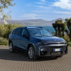 Leapmotor B10 REEV, un SUV elettrico dal design moderno, parcheggiato su un selciato con vista su un lago e colline verdi.