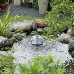 Un bassin d'eau avec une fontaine bulle, entouré de rochers et de verdure. Idéal pour fabriquer une cascade en bois.