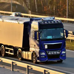 Niebieska ciężarówka z naczepą na autostradzie.