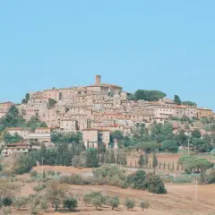 Panoramica di Casale Marittimo, un borgo medievale toscano arroccato su una collina, con case in pietra e tetti rossi, circondato da ulivi e cipressi.