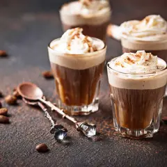 Kawa mocha z ekspresu, udekorowana bitą śmietaną i posypką, prezentuje się apetycznie.