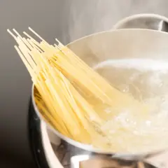 Kluska spaghetti zanurza się w gotującej wodzie. Czy wode na makaron sie soli? Tak, aby nadać jej smak.