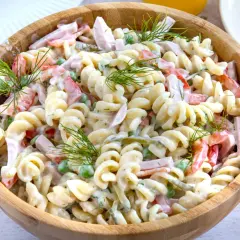 Ein cremiger Nudelsalat mit Schinken, Erbsen und Paprika, garniert mit Dill. Ein leckeres nudelsalat rezept für jede Gelegenheit.