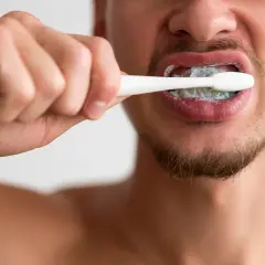 Hombre cepillándose los dientes con pasta. ¿Cuánto tiempo hay que lavarse los dientes? Dos minutos es lo recomendado.