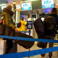 Osoby z bagażem sportowym, w tym futerałem na instrument, czekają na odprawę na lotnisku. Idealny bagaż sportowy Ryanair na podróż.