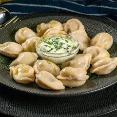 Pyszne pierogi z mięsem z rosołu, podane z gęstą śmietaną i koperkiem. Idealne na obiad.