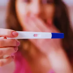 Kobieta trzyma test ciążowy z dwoma kreskami. To może być początek nowej historii, l4 w ciąży.