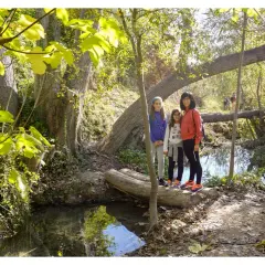 Familia posa en la ruta del agua Sella, disfrutando del sendero boscoso y el arroyo.