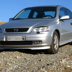 Srebrny Opel Astra G 1.6 16v na kamienistym podjeździe, gotowy na przygodę.
