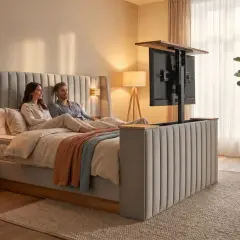 Ein Paar entspannt im Bett, während ein **Fernseher im Schlafzimmer** aus einem Bettgestell fährt.