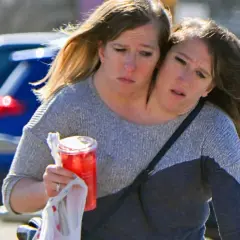 Bliźniaczki syjamskie Abby i Brittany idą razem, jedna z nich trzyma napój.