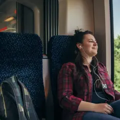 Ung kvinna lyssnar på musik i hörlurar under en resa med biltåg genom Europa.