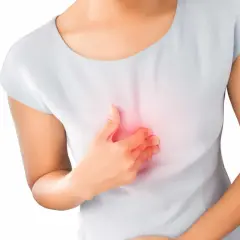 Kobieta trzyma się za klatkę piersiową, odczuwając pieczenie. To klasyczna zgaga po słodkim.