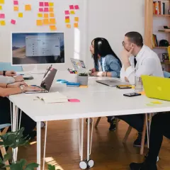 Zespół pracuje nad projektem, a tablica z notatkami sugeruje proces onboardingu.