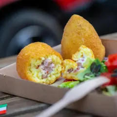 Arancini co to? Złociste kulki ryżowe z szynką i serem, podane z sałatką. Pyszna włoska przekąska.