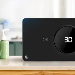 Purificador de aire AIRFY OZONO, con temporizador digital y controles táctiles. Junto a toallas y dispensadores de jabón, ideal para un ambiente fresco.