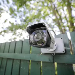 Cámara de seguridad montada en una valla verde. Ideas de camuflaje para ocultar cámaras.