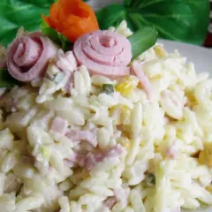 Pyszna sałatka z makaronem ryżowym, szynką i ogórkiem, udekorowana różyczkami z szynki i marchewki.