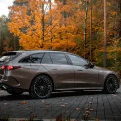 Brązowy Mercedes E300de kombi na tle jesiennego lasu.