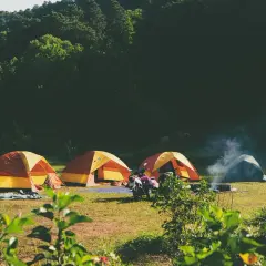 Namiotowe miasteczko w Bieszczadach. Dym z ogniska unosi się nad zielonymi namiotami, a motocykl czeka na przygodę.